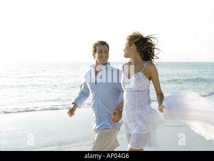 Couple walking on beach, smiling at each other Banque D'Images