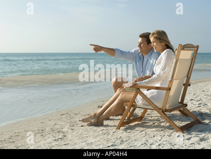 Couple assis dans des chaises longues sur la plage Banque D'Images