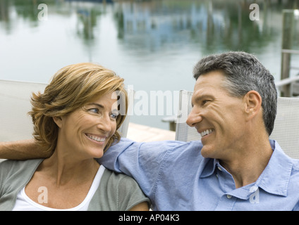 Couple près de l'eau, smiling at each other Banque D'Images