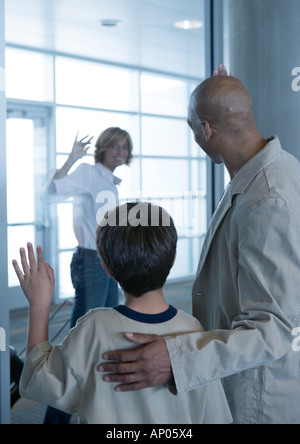 Woman waving goodbye à man and boy in airport Banque D'Images