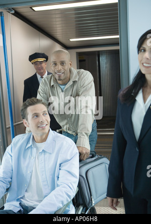 L'homme en fauteuil roulant poussé in airport Banque D'Images
