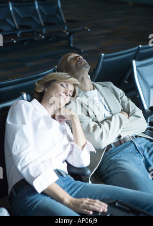 Travelers sleeping in airport lounge Banque D'Images