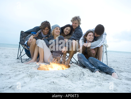 Groupe de jeunes amis assis à côté de camp sur la plage Banque D'Images