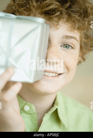 Boy holding up present in front of face Banque D'Images