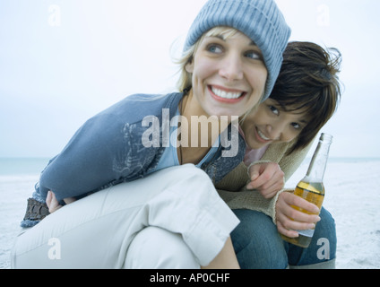 Deux amies sur la plage, avec une bouteille de bière Banque D'Images