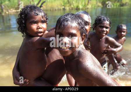 Les enfants autochtones de Ramingining se rafraîchir et jouer dans le crocodile-libre à Japidi billabong Japin Arnhem Land NT Australie Banque D'Images
