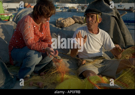 L'Europe, Grèce, Îles du Dodécanèse, Leros : pêcheur réparant ses filets à Pandeli Harbour Banque D'Images