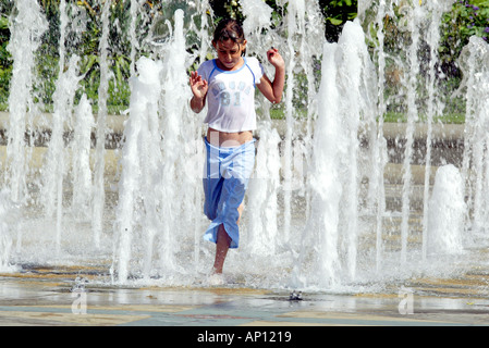 Une jeune fille court à travers les fontaines de jardin de paix à Sheffield South Yorkshire Banque D'Images