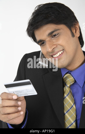 ANG200085 Executive holding mobile phone entre l'épaule et de la tête à la carte de crédit à Banque D'Images