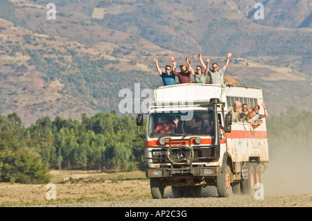 Un overland truck en vitesse sur un chemin de terre avec les passagers forme du toit sièges et windows du chariot. Banque D'Images