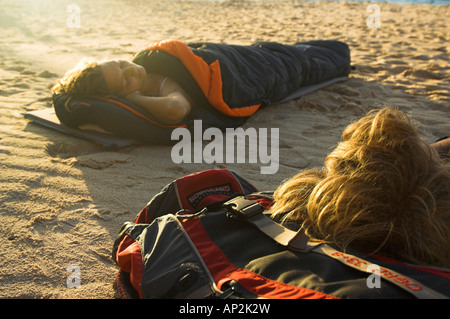 Jeune couple dans des sacs de couchage sur la plage Banque D'Images