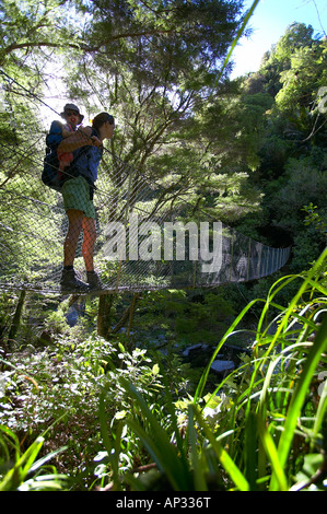 La mère et l'enfant sur pont suspendu, rivercrossing en parc national Abel Tasman, côte nord de l'île du Sud, Nouvelle-Zélande Banque D'Images