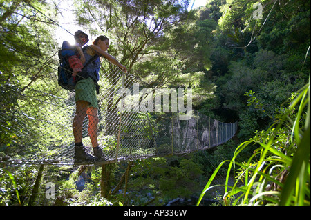 La mère et l'enfant sur pont suspendu, rivercrossing en parc national Abel Tasman, côte nord de l'île du Sud, Nouvelle-Zélande Banque D'Images