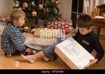 Deux garçons ouverture présente en vertu de l'arbre le matin de Noël Banque D'Images