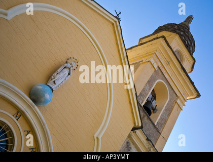 Regardant les clocher d'une petite église jaune près du village italien de Glori défini dans un ciel bleu clair, Italie Banque D'Images