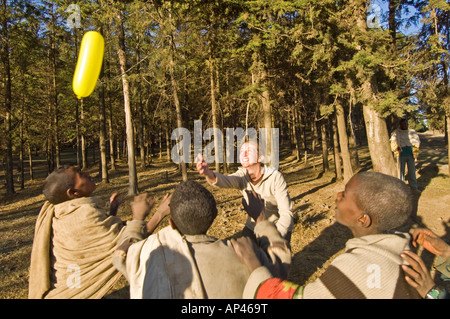 Un touriste à jouer avec les enfants essayant d'attraper un ballon. Banque D'Images