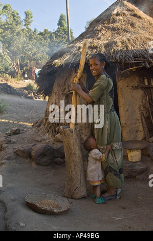 Une mère et son bébé devant sa maison à Lalibela le meulage de l'orge. Banque D'Images