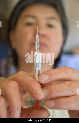 Femme la préparation d'une dose d'Interféron pour l'auto-administration par aiguille hypodermique Banque D'Images