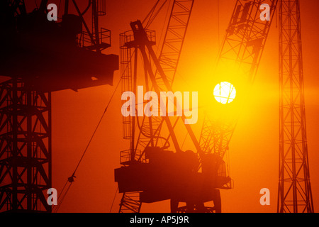 Construction grues à tour au coucher du soleil. Banque D'Images