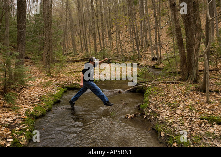 Un garçon joue dans le ruisseau du Golfe au début du printemps. Pepperell, MA. Banque D'Images