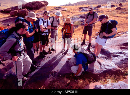 Un guide marocain et un groupe de trekkeurs regarder sculptures préhistoriques à l'Oukaimeden, Haut Atlas nr Marrakech, Maroc Banque D'Images