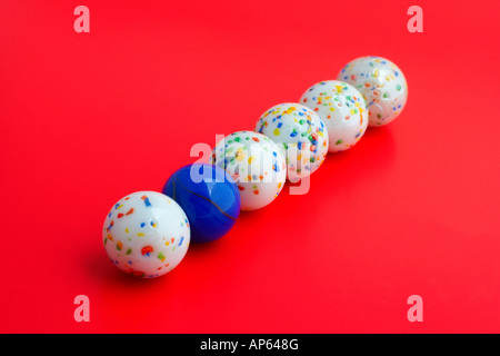 Une balle bleue parmi cinq boules blanches se concentrer sur boule bleue avec fond rouge DOF peu profondes Banque D'Images