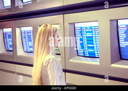 Young businesswoman affichage de l'information sur les moniteurs à l'aéroport Banque D'Images