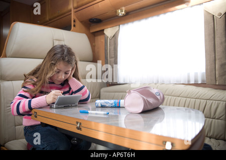 Petite fille assise dans un camping-car jouer avec nintendo ds Banque D'Images