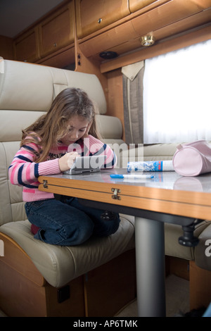 Petite fille assise dans un camping-car jouer avec nintendo ds Banque D'Images