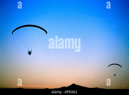 Des silhouettes en parapente au-dessus de ciel coucher de soleil du désert Banque D'Images