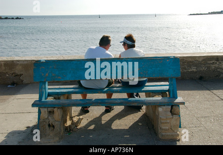 Couple d'âge moyen s'assit sur un banc face à la mer sur la promenade à Pafos sur la Méditerranée orientale de l'île de Chypre Banque D'Images