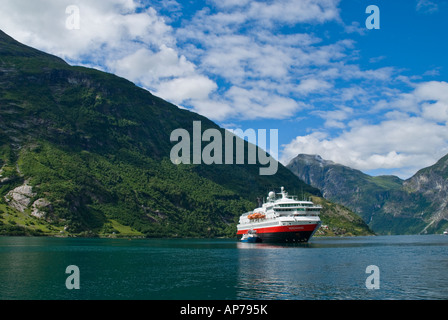 Ferry Hurtigruten à port à Geiranger et entouré par les montagnes du Geirangerfjord, Norvège Banque D'Images