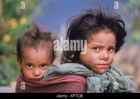 Jeune fille portant son bébé frère ou sœur à dos au village de l'Himalaya au Népal Banque D'Images