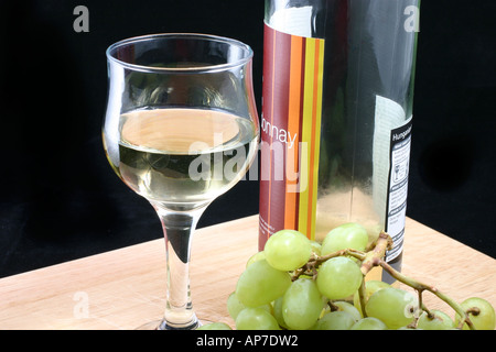 Verre de vin blanc avec des raisins et bouteille Banque D'Images