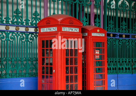 Deux boîtes de téléphone rouge britannique traditionnel victorien colorés contre la ferronnerie, London, England, UK Banque D'Images