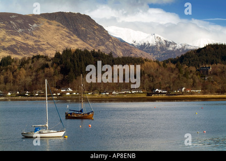 Bateaux à voile flotter doucement sur un loch écossais calme entouré par des montagnes couvertes de neige écossais et un village de réchauffer winte Banque D'Images