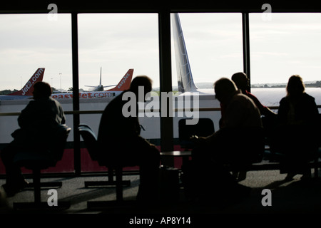 Les passagers qui attendent dans le salon en face de la fenêtre à l'aéroport international de Belfast en Irlande du Nord Banque D'Images