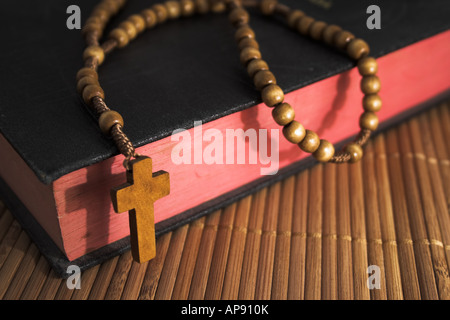 Bible fermée avec chapelet sur un matelas de paille /// crucifix croix Christianisme Catholique Chrétienne de perles en bois Bois de conviction catholique Christ saint livre Banque D'Images