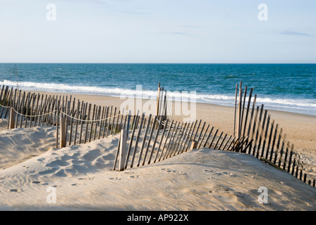 Les vagues de l'océan, sur les rails de la plage de sable avec des dunes et de contrôle de l'érosion en clôture du premier plan, les bancs extérieurs en Caroline du Nord. Banque D'Images