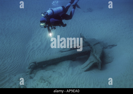 Scuba Diver met en lumière les old anchor sur un sable stérile Banque D'Images