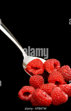 Cuillère à dessert en argent avec des framboises fraîches sur fond noir Banque D'Images