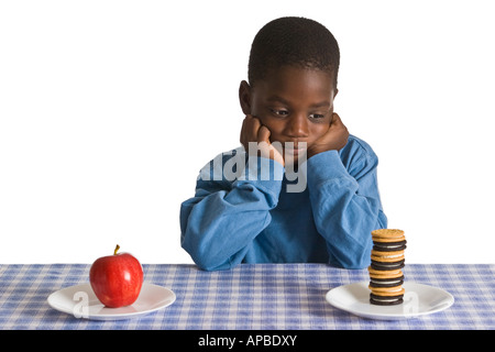 Un jeune garçon afro-américain se prépare pour une collation. Studio shot isolé sur blanc. Banque D'Images