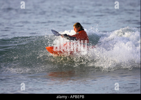 Des promenades en kayak masculin une vague dans la mer au large de la plage de White Rocks Portrush le comté d'Antrim en Irlande du Nord Banque D'Images