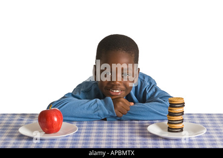 Un jeune garçon afro-américain se prépare pour une collation. Studio shot isolé sur blanc. Banque D'Images