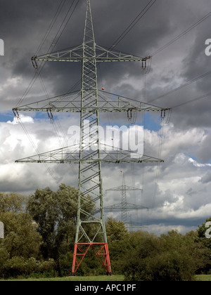 Les lignes d'alimentation, les mâts actuel vers l'épaissir le noir des nuages orageux. Banque D'Images