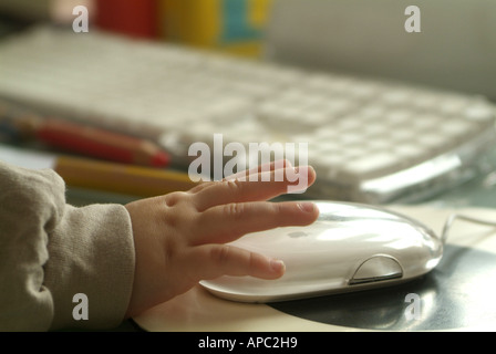 Garçon de deux ans s'intéresse aux momies PC et joue avec la souris de l'ordinateur. Banque D'Images