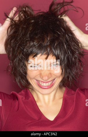 Jeune femme courir ses doigts dans ses cheveux Banque D'Images