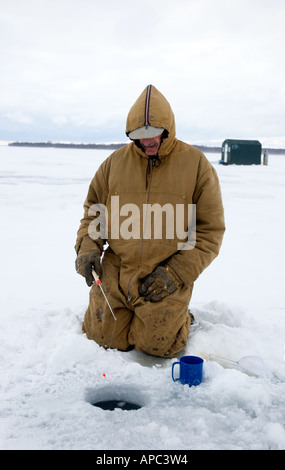 Man Ice fishing ; glace Hut en arrière-plan Banque D'Images