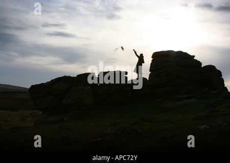 Silhouette d'girl flying kite on rock formation dans la lande de Dartmoor, dans le Devon, England UK Banque D'Images