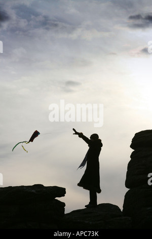 Silhouette d'girl flying kite on Hay Tor roches, Dartmoor, Devon, England UK Banque D'Images